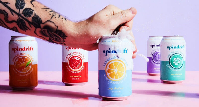 Tattooed person opening a can of Spindrift seltzer